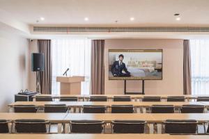 a lecture room with a screen with a man on it at GreenTree Inn Jiangsu Huai'an Qiangjiangpu District Shuidukou Avenue in Huai'an