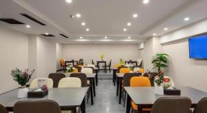 a waiting room with tables and chairs and a screen at Green Tree Inn Express Heze University Town in Heze