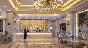 un homme debout dans le hall d'un hôtel dans l'établissement Vienna Hotel Yueyang East Station, à Yueyang