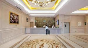 a man standing in a hotel lobby with a counter at Vienna Hotel Guangdong Zhongshan South Area Passenger Station in Zhongshan