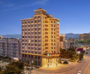 a large yellow building with a clock on it at Vienna Hotel Yunnan Dali Erhai Lake in Dali