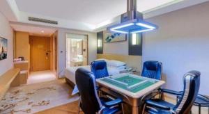 a room with a bed and a table and chairs at Vienna Hotel Guangdong Zhongshan Xiaolan High-Speed Railway Station in Zhongshan
