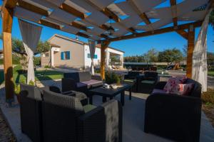 un patio con sillas y mesas bajo una pérgola de madera en Villa Tara, en Tinj