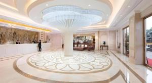 a man standing in a lobby with a large ceiling at Vienna Hotel Jiangxi Ji'an Anfu in Ji'an