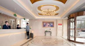 a lobby with two people standing at a counter at Vienna Hotel Hebei Hengshui High-Speed Railway Station in Hengshui
