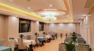 a dining room with tables and chairs and a chandelier at Vienna Hotel Zhejiang Lishui Qingtian Post Building in Lishui