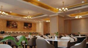 a dining room with tables and white chairs at Vienna Hotel Jiangxi Yongxin Shizheng Square in Yongxin