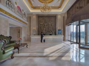 un homme debout dans un hall avec un grand tableau sur le mur dans l'établissement Vienna Hotel Anhui Lujiang International Building Materials Market Wuzhong, à Lujiang