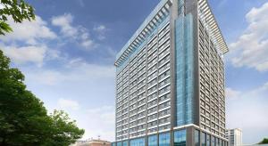 a tall glass building with a blue sky at Vienna Hotel Shandong Qingzhou Ancient City in Yanghe