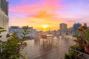 a balcony with chairs and a table and a sunset at Thank You Hotel Sanya Bay Coconut Dream Corridor Branch in Sanya