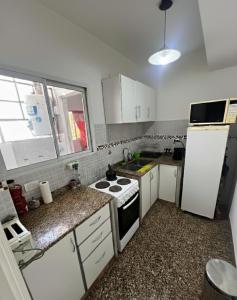 a kitchen with a stove and a white refrigerator at Check and Home - Peatonal II - 6 Huéspedes en el Centro a 3 cuadras de la Playa in Mar del Plata