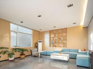 a living room with a blue couch and a table at GreenTree Inn Express Qingdao Jiaodong International Airport in Qingdao