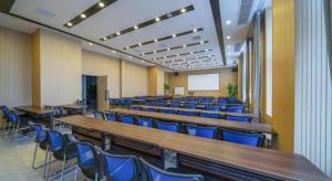 a lecture hall with wooden tables and blue chairs at Borrman Hotel Zhangzhou Baolong Plaza in Zhangzhou