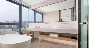 ein Badezimmer mit Badewanne und großem Spiegel in der Unterkunft Ramada Encore by Wyndham Jinan Shanghe in Shang-ho-hsien + 138 Fotos