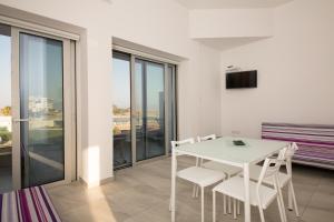 a white dining room with a white table and chairs at Christopher's Sandy Beach Suites in Ayia Napa