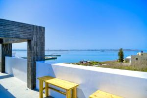 Un taburete de madera en una pared blanca con vista al agua. en 覓海海景會館民宿, en Magong