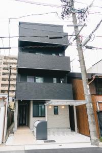 ein Gebäude mit schwarzem Dach auf einer Straße in der Unterkunft Otter Stay - Takaoka in Aoichō