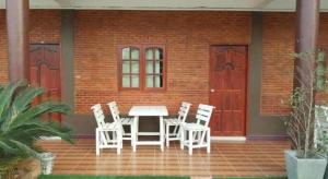 a patio with white chairs and a table and two doors at Sweet Home Chiangkhan in Chiang Khan