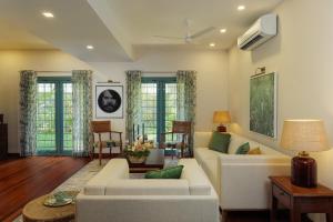 a living room with white furniture and green pillows at Mammootty House Kochi - a VKation Experience in Cochin