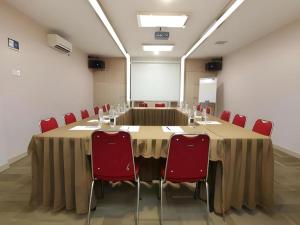 a conference room with a long table and red chairs at Lovina Inn Hotel Batam in Nagoya
