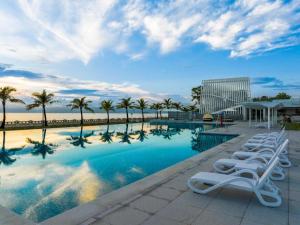 a row of white lounge chairs next to a swimming pool at Ocean Spring Metropark Hotel Zhuhai in Zhuhai