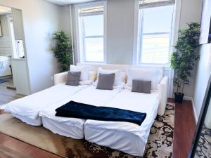 a large white bed in a room with windows at 3 Bedroom Smart Apartment Sleeps 11 with Parking Near Times Square in West New York