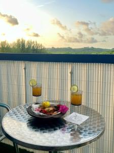 a table with a bowl of food and two glasses of juice at Kimia studio 2 pas de la plage au Gosier in Le Gosier