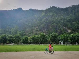 Una donna in bicicletta con un bambino sopra. di Phuphayot Resort a Trang
