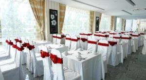 a room filled with white tables and chairs with red bows at New Palace Bac Lieu Hotel in Bạc Liêu +156 photos