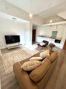 a living room with a brown couch and a television at St Okes Apartment- Peaceful retreat set in native bush Stay 1 night, 1 week or 1 month in Lower Hutt
