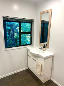a white bathroom with a sink and a window at St Okes Apartment- Peaceful retreat set in native bush Stay 1 night, 1 week or 1 month in Lower Hutt +9 photos