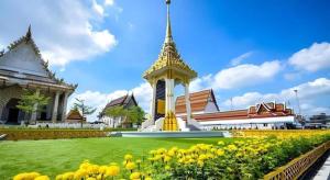 un edificio con una torre dell'orologio in un campo di fiori di Sweet Hug Hotel a Suphanburi