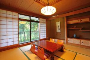 uma sala de jantar com uma mesa de madeira e cadeiras laranja em Guesthouse E-ne em Oshino