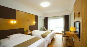 a hotel room with two beds and a television at Vatica Hangzhou Linan Qianwang Street Hotel in Hangzhou