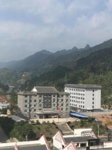 a large white building with mountains in the background at Lavande Hotels·Qiannan Libo in Libo