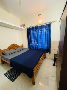 a bedroom with a bed with blue sheets and a window at Shriyaamvitha Homestays in Madikeri