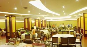 a restaurant with tables and chairs and people in it at New Friendship Hotel in Luoyang
