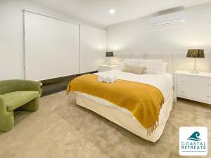 a bedroom with a large bed and a green chair at Rilley Retreat Inverloch, Luxe Townhouse Near Beach in Inverloch