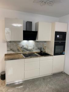 a kitchen with white cabinets and a sink and a stove at Downtown Apartment in Bonn