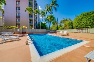 a swimming pool with chairs and a building at Private Lanai! - AC -5 minute walk from beach! in Lahaina