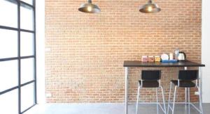 a brick wall with a table and two stools at L22 HOSTEL in Bangkok