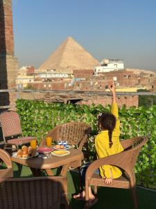 a woman sitting at a table with her arm in the air at Great Pyramids view Lodge in Cairo