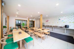 a restaurant with wooden tables and green chairs at Vatica Hefei Feidong County Yuzhou Central Square Hotel in Hefei