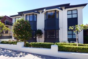 a house with black windows and bushes in front of it at Avoca Randwick by Sydney Lodges in Sydney