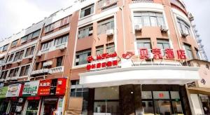 a pink building with red chairs on top of it at Shell Shanghai Songjiang District Xinqiao Town Xinqiao Hotel in Chunshen
