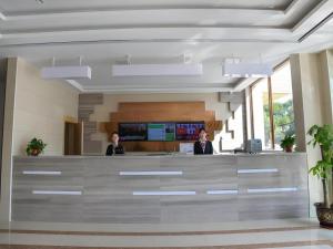 two people standing at a reception desk in a lobby at GreenTree Inn Express Gongqing City Nanchang University in Gongqingcheng