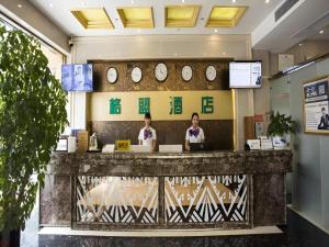 two women sitting at a counter in a lobby with clocks at GreenTree Alliance Hotel Chongqing Qianjiang County Wuling Shui'an Jiaotong Xi Road in Qianjiang