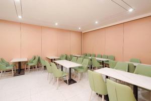 a classroom with tables and green chairs in a room at GreenTree Inn xinghua Middle Yingwu Road Express Hotel in Xinghua