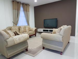 uma sala de estar com duas cadeiras e uma televisão em Ummi Guesthouse em Dungun