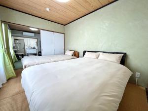 two beds in a small room with white sheets at Powder Snow 粉雪 in Furano